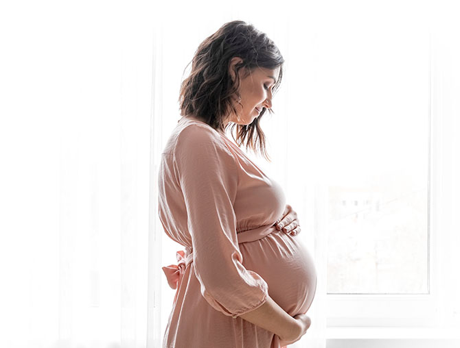 A smiling pregnant woman holding her belly